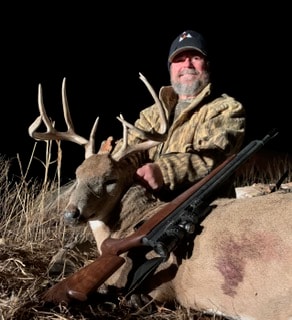 Hunter with trophy buck and rifle